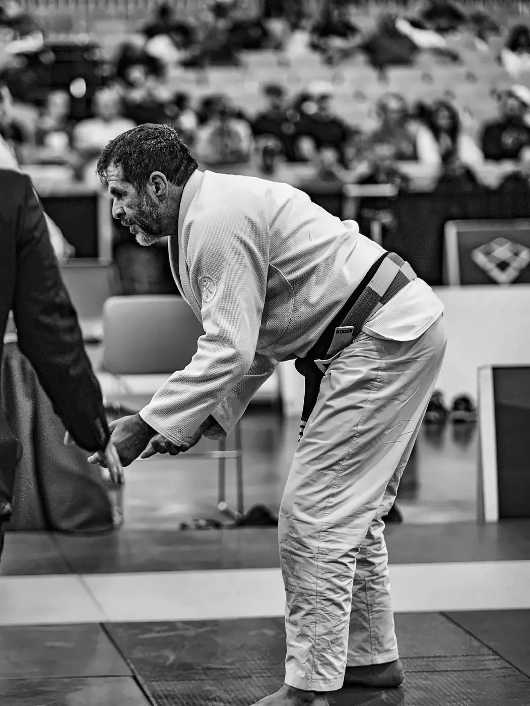 Wagner Mota greets the referee on the mat, in black and white